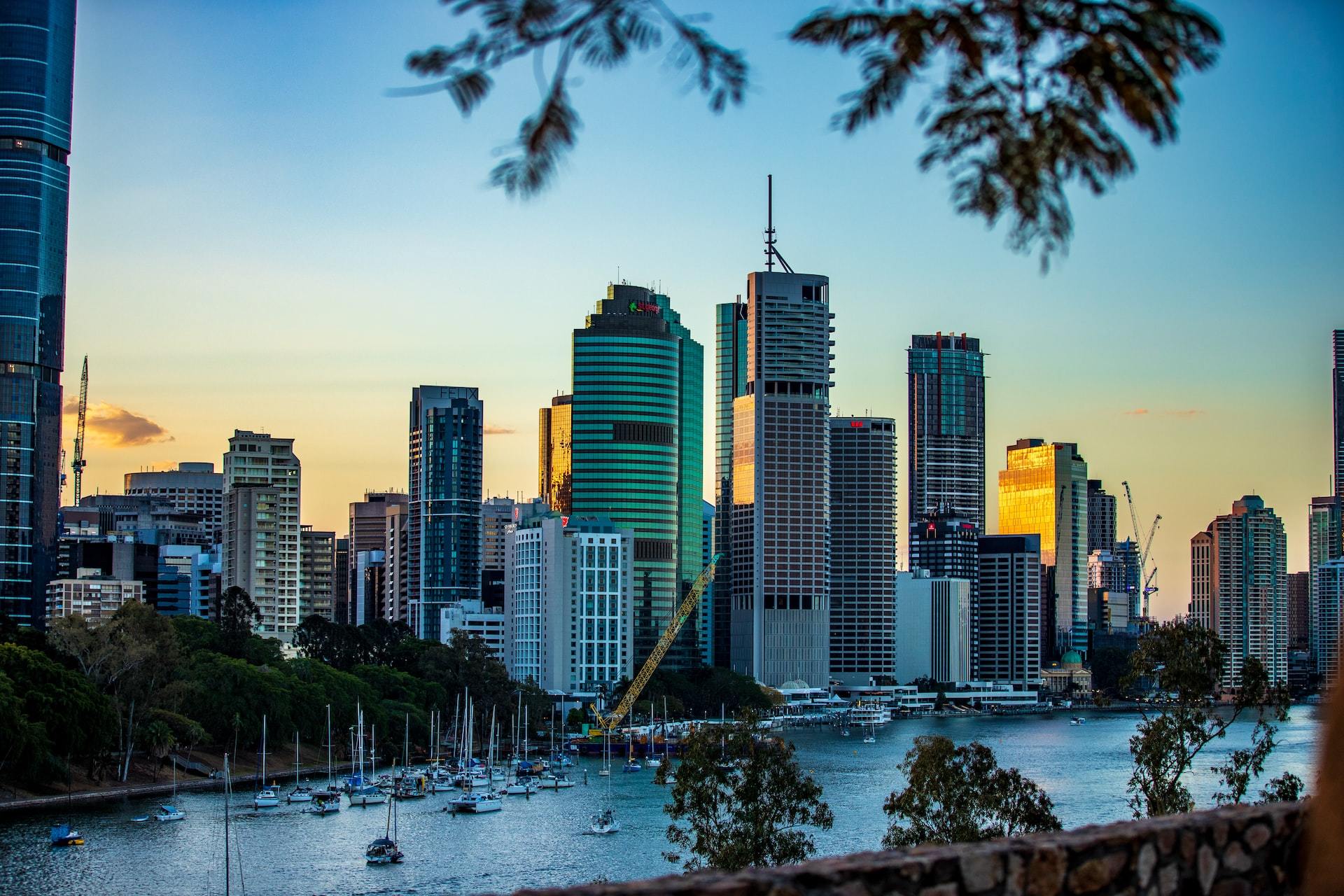 Brisbane's downtown during golden hour with sailboats in the foreground.