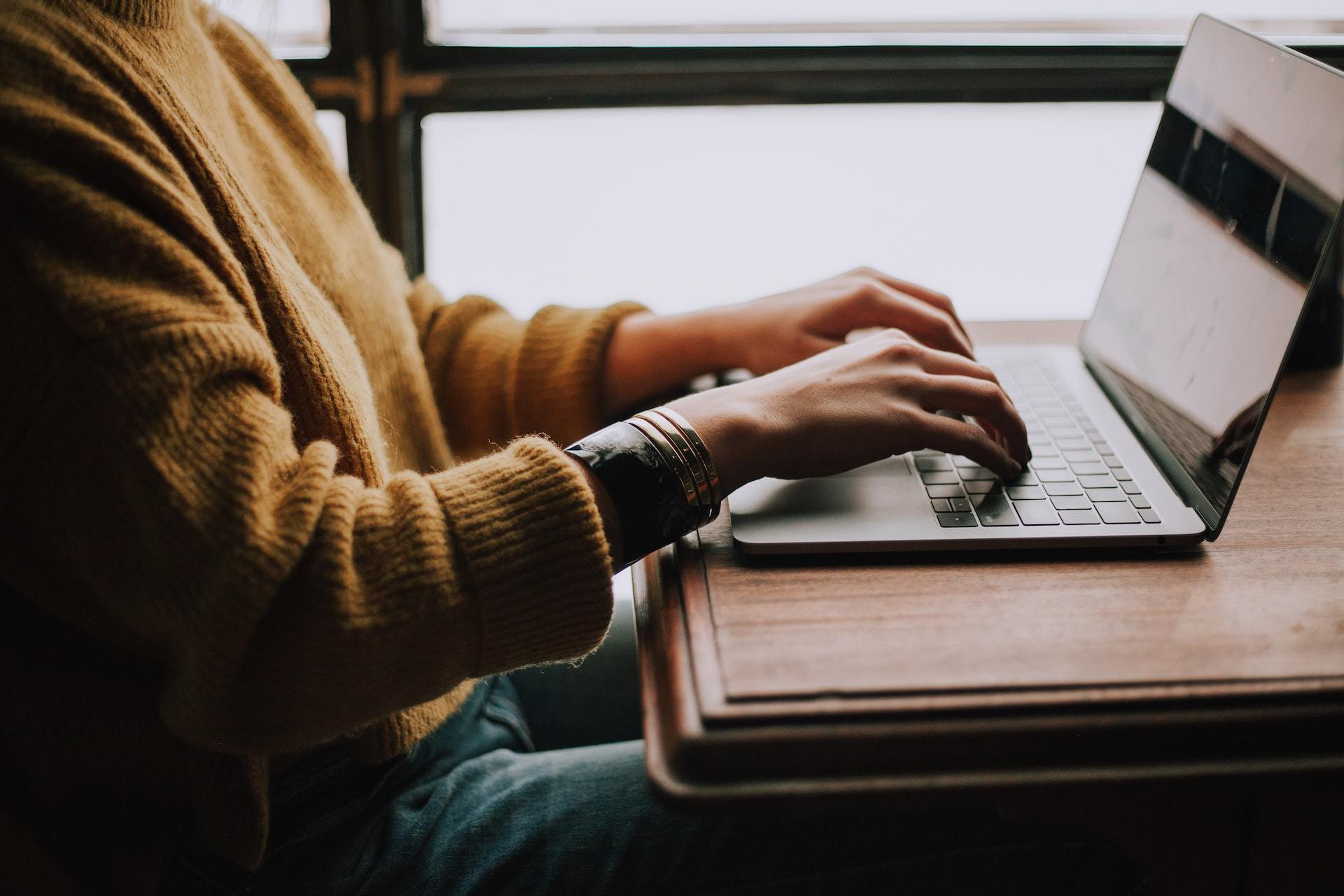 A woman typing on a MacBook computer.