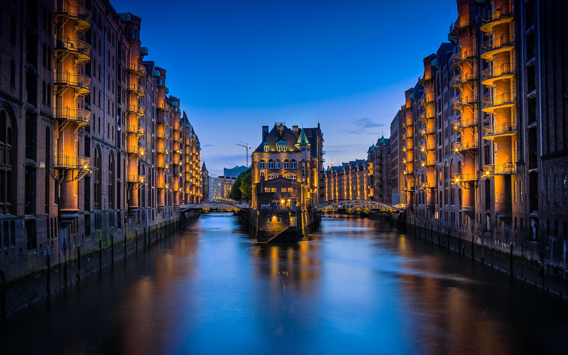 A canal between buildings lit up during nighttime.