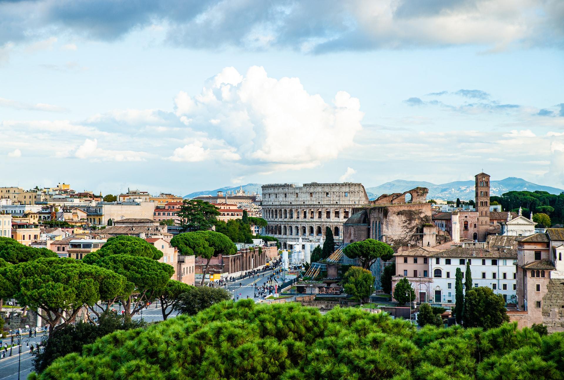 In Rome, the ancient architecture mixes with more modern accoutrements under a blue sky and clouds.