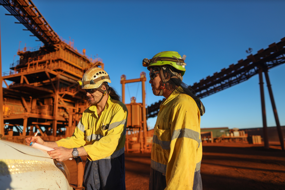 Miner supervisor engineer wearing safety fall protection helmet read and sign permit to work before hand over working at height paper book to contractor construction mine site in Sydney, Australia.