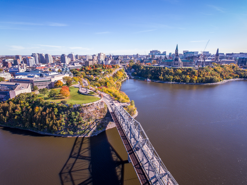 Autumn aerial photo of the city of Ottawa with a pedestrian bridge over the Ottawa river.