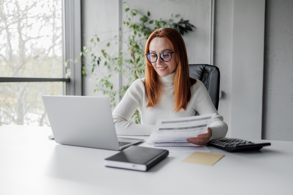 Businesswoman with invoices and documents calculating rates and KPIs.